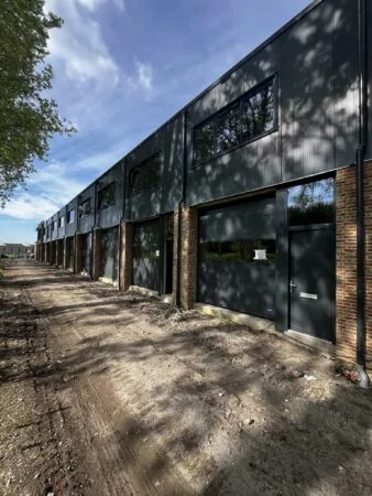 Rij nieuwbouw bedrijfsunits aan de Broekdijk West met moderne gevels en onverharde toegangsweg.